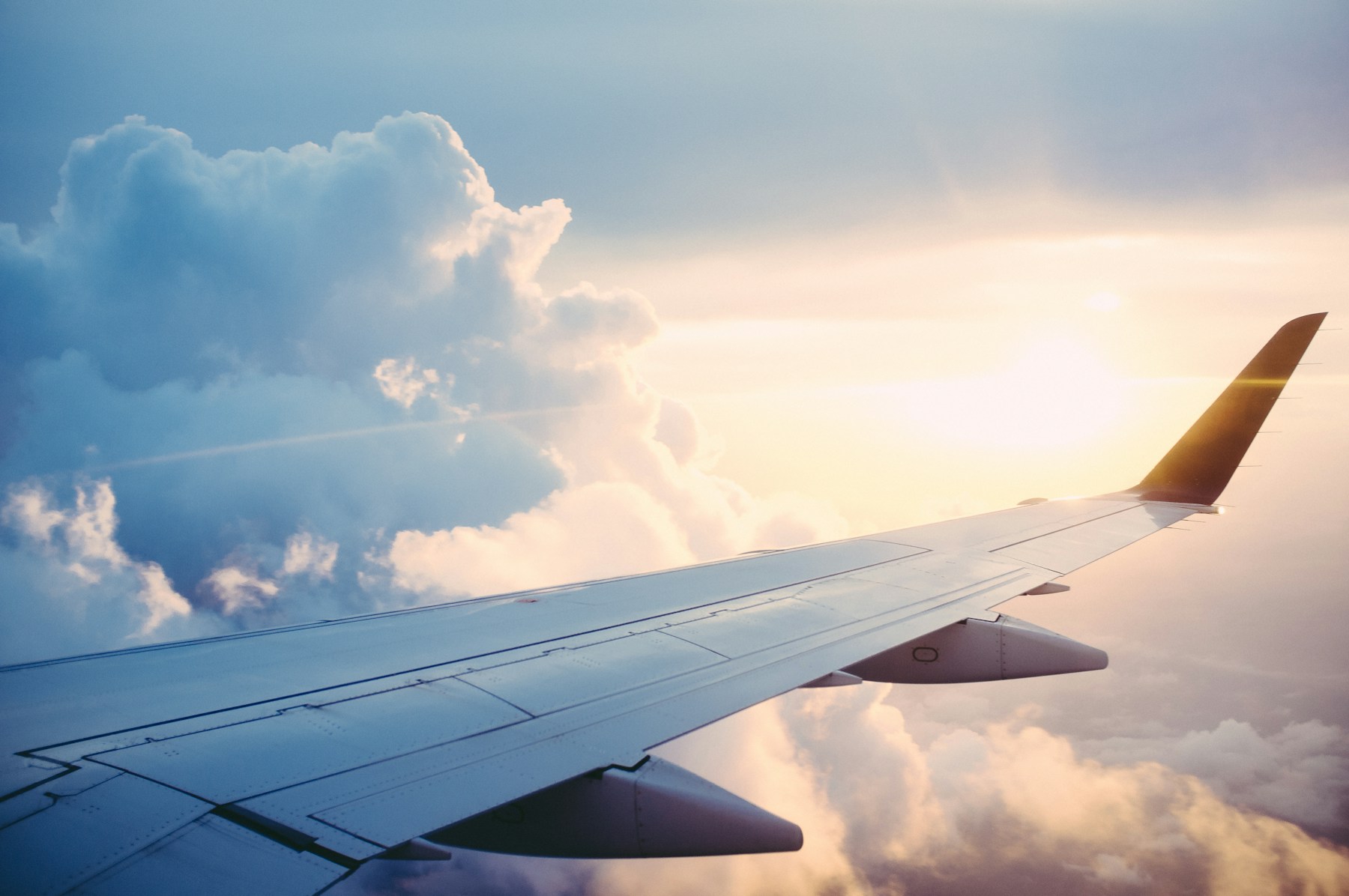 An airplane wing above clouds at sunrise